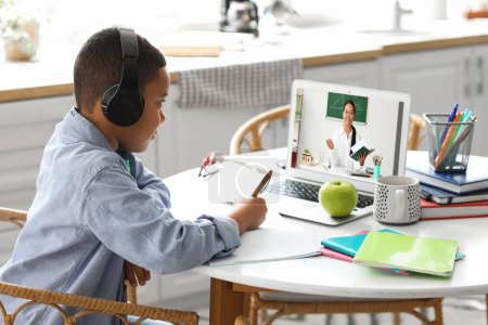 Photo for Little African-American boy in headphones studying at home. Concept of online education - Royalty Free Image