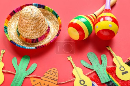 Photo for Mexican maracas with sombrero hat and paper garland on red background, closeup - Royalty Free Image