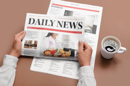 Woman reading newspaper with cup of coffee on brown background
