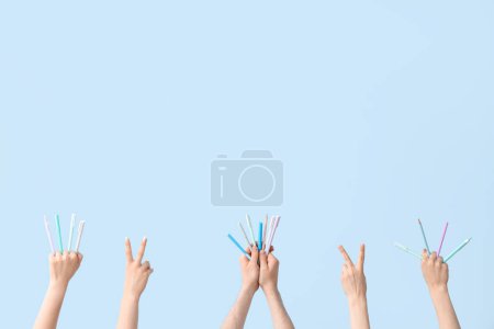 Téléchargez les photos : Mains avec différents stylos sur fond bleu - en image libre de droit
