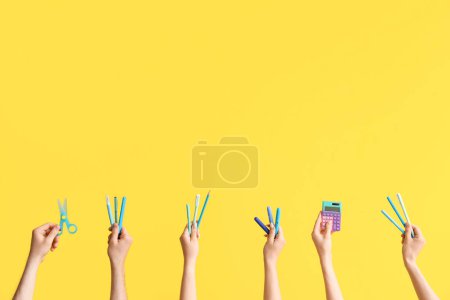 Téléchargez les photos : Hands with school supplies on yellow background - en image libre de droit