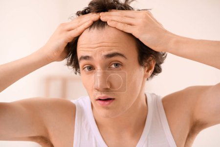 Hombre joven con problemas de pérdida de cabello en el baño, primer plano