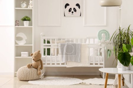 Téléchargez les photos : Élégant intérieur de la chambre des enfants dans des tons blancs avec lit bébé et étagère - en image libre de droit