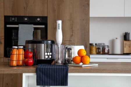 Foto de Multi cocina, licuadora, tostadora y escamas con naranjas en la mesa de madera en la cocina - Imagen libre de derechos