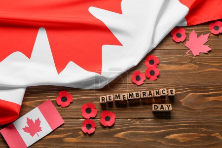 Foto de Flores de amapola con banderas de Canadá sobre fondo de madera. Día del Recuerdo - Imagen libre de derechos