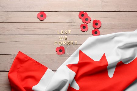 Foto de Flores de amapola con bandera de Canadá y texto para que no olvidemos sobre fondo de madera. Día del Recuerdo - Imagen libre de derechos