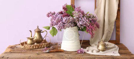 Téléchargez les photos : Composition avec bouquet de fleurs de lilas et ensemble de thé sur table en bois près du mur - en image libre de droit
