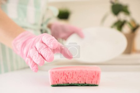 Mujer tomando esponja de limpieza en la cocina, primer plano