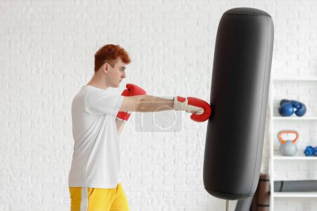 Téléchargez les photos : Jeune boxeur rousse sac de boxe dans la salle de gym - en image libre de droit