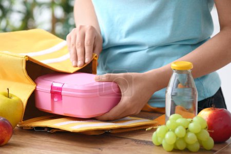 Mujer embalaje comida fresca en bolsa de almuerzo en la cocina
