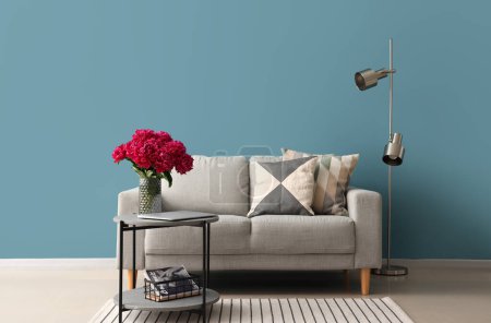Téléchargez les photos : Vase de pivoines rouges avec table basse, canapé et lampadaire près du mur bleu - en image libre de droit