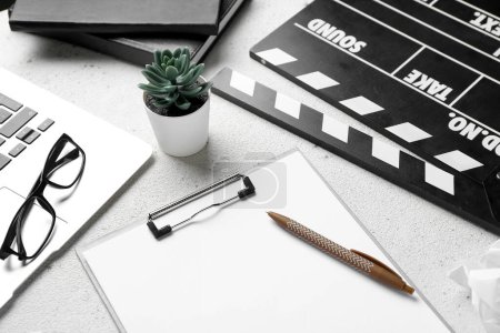 Photo for Clipboard with movie clapper, plant, eyeglasses and laptop on white background - Royalty Free Image