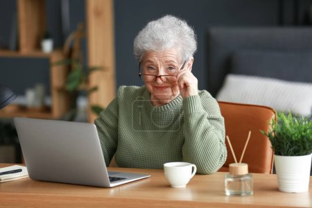 Seniorin sitzt mit Laptop im Büro