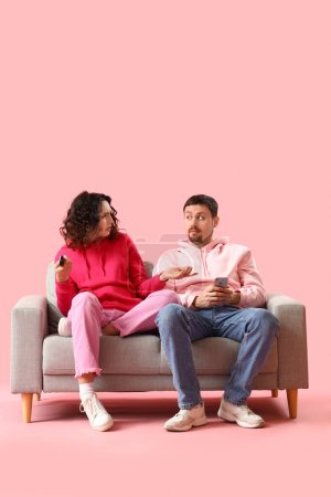 Photo for Young couple watching TV on pink background - Royalty Free Image