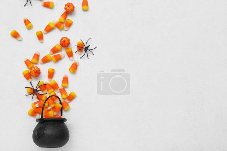 Photo for Bowl with tasty Halloween candy corns and spiders on light background - Royalty Free Image