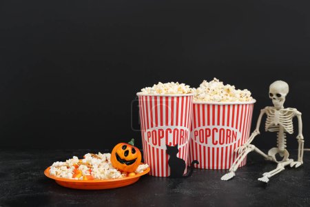 Composition with tasty popcorn and skeleton on dark background. Halloween celebration