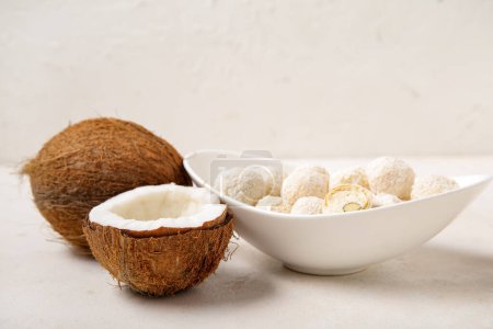Téléchargez les photos : Bol avec bonbons au chocolat blanc et noix de coco sur table lumineuse - en image libre de droit