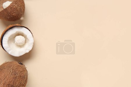 Téléchargez les photos : Noix de coco avec bonbons au chocolat blanc sur fond beige - en image libre de droit