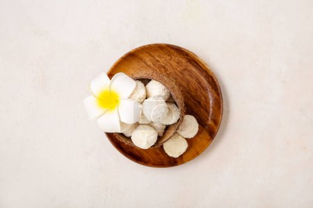 Téléchargez les photos : Coque de noix de coco avec bonbons au chocolat blanc et fleur de plumeria sur table lumineuse - en image libre de droit