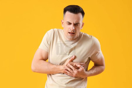 Photo for Young man having heart attack on yellow background - Royalty Free Image