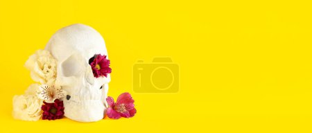 Téléchargez les photos : Crâne humain avec de belles fleurs sur fond jaune avec espace pour le texte - en image libre de droit