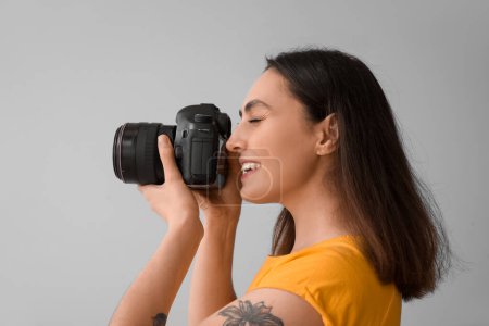 Photo for Female photographer with professional camera on grey background, closeup - Royalty Free Image