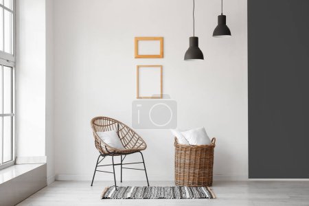 Wicker armchair and basket with pillows near white wall