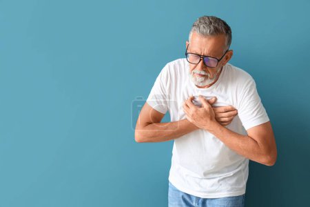 Photo for Mature man having heart attack on blue background - Royalty Free Image
