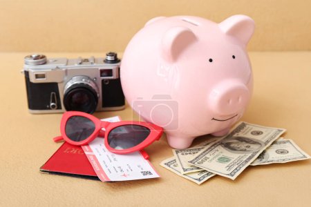 Foto de Hucha con dinero, cámara fotográfica y pasaporte sobre fondo naranja. Concepto de ahorro para viajes - Imagen libre de derechos