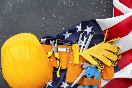 Photo for Belt with different tools, hardhat and USA flag on grey grunge background. Labor Day celebration - Royalty Free Image
