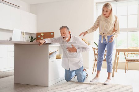 Photo for Mature woman and her husband having heart attack in kitchen - Royalty Free Image