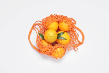 Téléchargez les photos : Sac en maille avec des oranges fraîches sur fond blanc - en image libre de droit