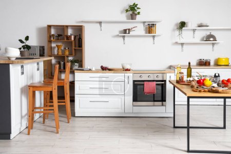 Foto de Interior de cocina ligera con mostradores blancos, estantes y mesa - Imagen libre de derechos