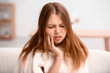 Young woman suffering from  toothache at home
