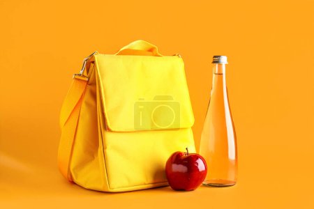 Téléchargez les photos : Sac boîte à lunch avec pomme et bouteille d'eau sur fond orange - en image libre de droit
