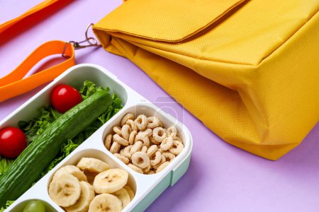 Téléchargez les photos : Sac et boîte à lunch avec des aliments savoureux sur fond lilas - en image libre de droit