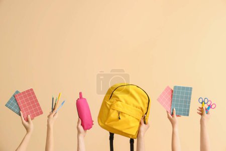 Téléchargez les photos : Mains tenant des fournitures scolaires sur fond beige - en image libre de droit