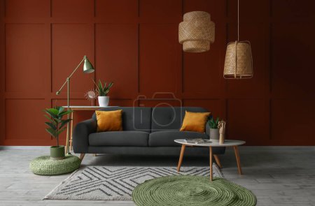 Téléchargez les photos : Intérieur du salon avec canapé élégant, tables et lampes près du mur brun - en image libre de droit