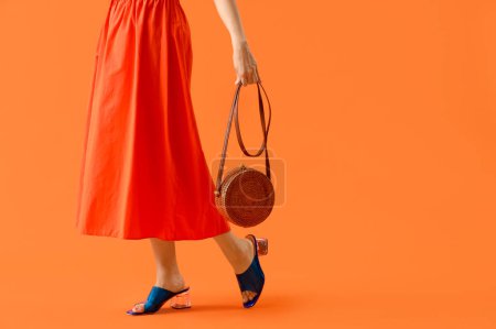 Foto de Hermosa mujer en ropa de verano y con bolsa sobre fondo naranja - Imagen libre de derechos