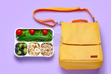 Téléchargez les photos : Sac et boîte à lunch avec des aliments savoureux sur fond lilas - en image libre de droit