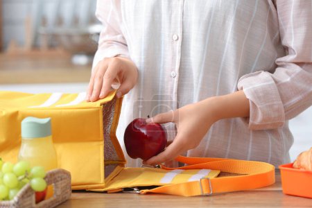 Téléchargez les photos : Femme emballant le repas frais dans le sac de boîte à lunch dans la cuisine - en image libre de droit