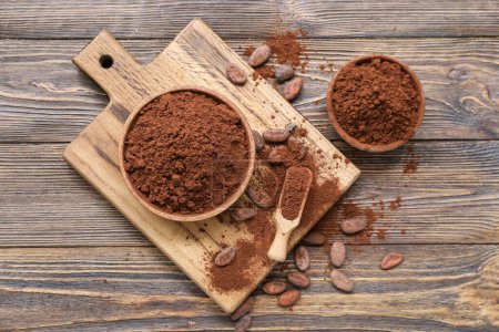 Foto de Cuencos con cacao en polvo y frijoles sobre fondo de madera - Imagen libre de derechos