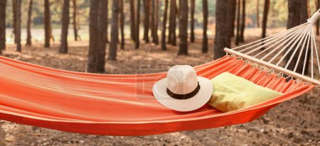 Hängematte mit Hut und Kissen im Wald an einem Sommertag