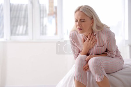 Foto de Mujer madura teniendo un ataque al corazón en el dormitorio - Imagen libre de derechos