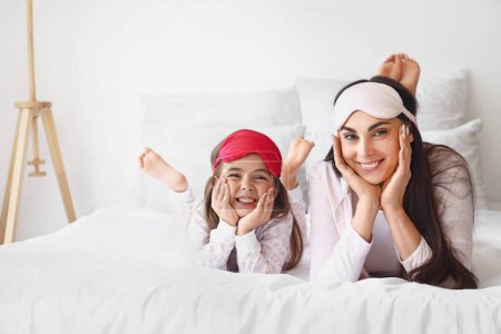 Photo for Happy mother and her little daughter with sleeping masks in bedroom - Royalty Free Image