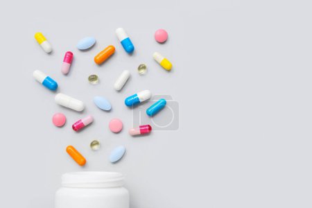 Composition with colorful pills and bottle on grey background