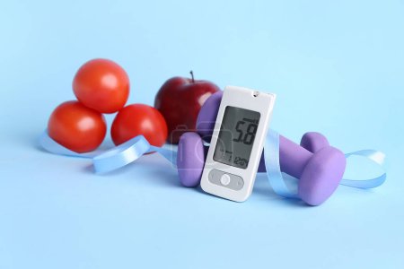 Photo for Glucometer with ribbon, dumbbells and food on blue background. Diabetes concept - Royalty Free Image