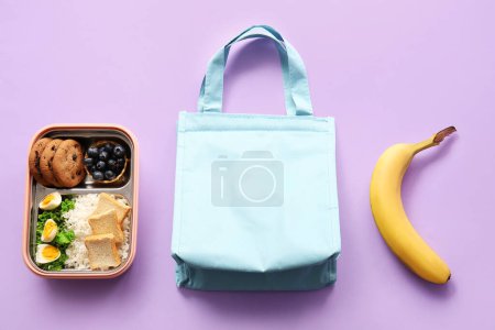 Téléchargez les photos : Sac, boîte à lunch avec délicieuse nourriture et banane sur fond lilas - en image libre de droit