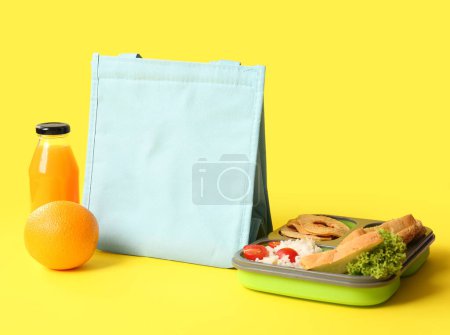 Photo for Bag, lunchbox with delicious food and bottle of juice on yellow background - Royalty Free Image