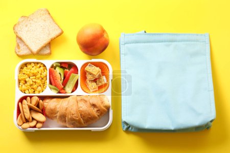 Téléchargez les photos : Sac et boîte à lunch avec de délicieux aliments sur fond jaune - en image libre de droit
